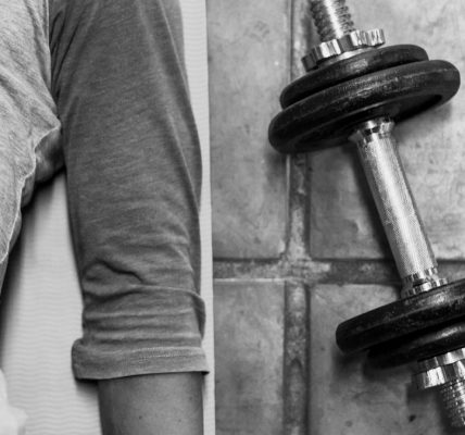 person in black pants and black socks holding dumbbell