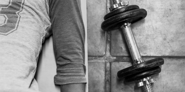 person in black pants and black socks holding dumbbell